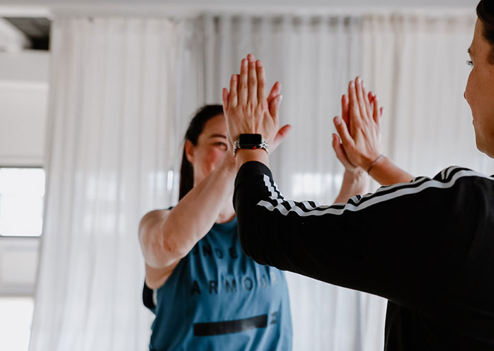 Trainer und Kundin feiern einen Fortschritt mit einem High Five
